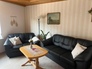 a living room with two black couches and a table at Haus Bernsteinsee mit Goitzsche-Schnuppersegeln in Friedersdorf