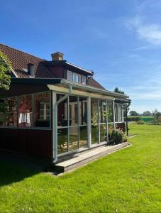 a house with a screened in porch on a lawn at precis intill Ombergs golfbana, nära till Vättern, stora Lund och Hästholmen in Ödeshög