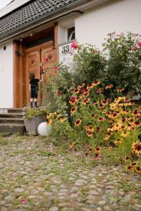 eine Person, die an der Tür eines Hauses mit Blumen steht in der Unterkunft Przystawy Agroturystyka in Malechowo
