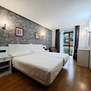 a bedroom with two beds and a brick wall at Hotel Ciudad Cangas de Onis in Cangas de Onís