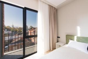 a bedroom with a bed and a large window at Doors Hotel in Tbilisi City