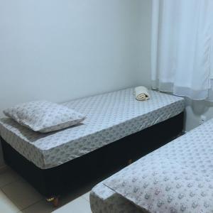two twin beds in a small room withthritisthritisthritisthritisthritisthritisthritisthritis at Elegância e Conforto no Centro da Cidade in Vespasiano