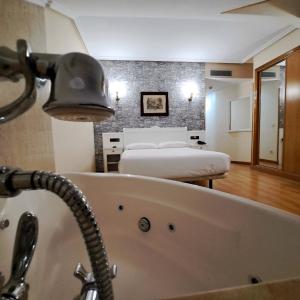 a bathroom with a bath tub and a room with two beds at Hotel Ciudad Cangas de Onis in Cangas de Onís