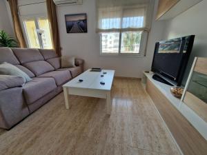 a living room with a couch and a flat screen tv at Beach Apartment Regueral in Cambrils