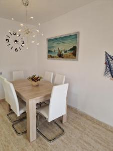 a dining room with a wooden table and white chairs at Beach Apartment Regueral in Cambrils