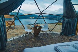 a tent with a table and chairs and a view of a lake at Glamping Nuna Experience in Andahuaylas