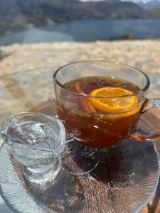 a glass cup of tea with an orange on a table at Glamping Nuna Experience in Andahuaylas