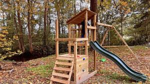um parque infantil de madeira com um escorrega e uma escada em Maison au cœur de la forêt 