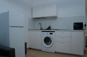 a white kitchen with a washing machine and a sink at VolcanoKite Apartments in Famara