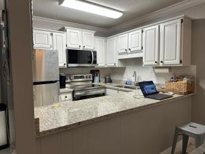 a kitchen with white cabinets and a laptop on a counter at 2-Bedroom Condo on Gulf Shores Beach w/Pool in Gulf Shores