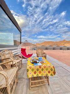 un patio con mesa, sillas y hamaca en WADi RUM ALi CAMP, en Wadi Rum