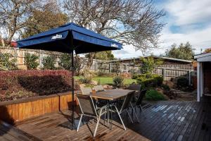 une table et des chaises avec un parasol bleu sur une terrasse dans l'établissement Convenient luxury home, minutes to CBD + hospital, à Launceston