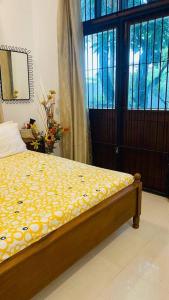 ein Schlafzimmer mit einem Bett mit gelber Decke und einem Fenster in der Unterkunft Catherine Villa in Ja Ela near Colombo Airport Expressway Exit in Ja-Ela