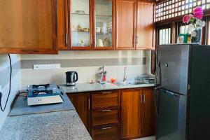 een keuken met houten kasten en een zwarte koelkast bij Catherine Villa in Ja Ela near Colombo Airport Expressway Exit in Ja-Ela