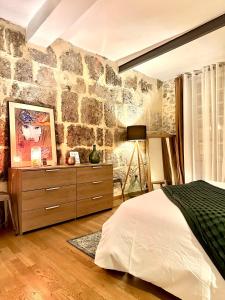 a bedroom with a stone wall with a bed and a dresser at Appartement Lavande et Jasmin in Anduze