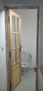 a bathroom with a toilet and a wooden door at Dar Fes Marrakech in El Hajeb