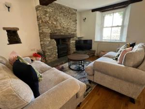 a living room with two couches and a stone fireplace at The Old Bakery, in the heart of St Ann's Chapel in Kingsbridge