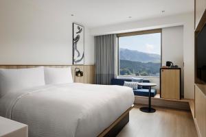 阿苏市Fairfield by Marriott Kumamoto Aso的一间带床和大窗户的酒店房间