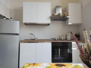 una cocina con armarios blancos y horno negro en La Villetta a Cuneo, en Cuneo