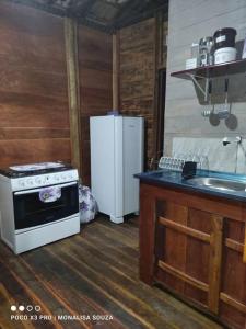 a kitchen with a stove and a refrigerator at LaCasinhaDeMadeira in Macaé