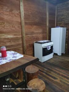 uma cozinha com um fogão, um frigorífico e uma mesa em LaCasinhaDeMadeira em Macaé