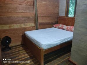 a small bed in a room with wooden walls at LaCasinhaDeMadeira in Macaé