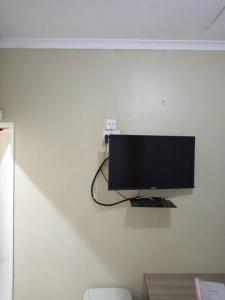 TV de pantalla plana colgada en una pared blanca en Casa MaSa Inn en Francistown