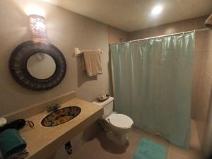 a bathroom with a sink and a toilet and a mirror at Hacienda Camelot in Cozumel