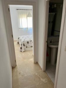 Habitación blanca con cama y baño. en Apartamento Pinares del Portil a pie de playa, en El Portil
