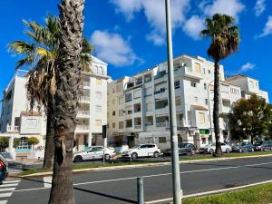 uma rua com palmeiras em frente a um edifício em Apartamento Pinares del Portil a pie de playa em El Portil