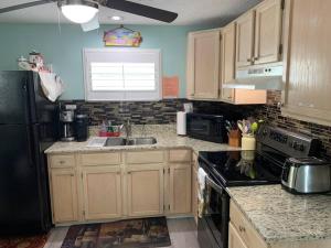 a kitchen with wooden cabinets and a black refrigerator at Bayside Cottage in Clearwater Beach
