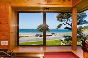 a window in a kitchen with a view of the ocean at Sandy Bay Beachfront in Matapouri