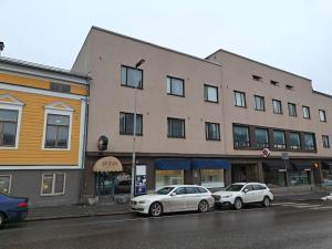 dois carros estacionados em frente a um edifício numa rua em Brooms - Newly renovated central studio apartment em Pietarsaari