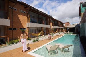 una mujer caminando por una piscina al lado de un edificio en Uri Pousada en Maragogi