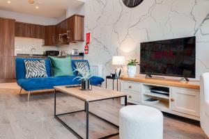 uma sala de estar com um sofá azul e uma televisão em City centre Top floor apartment in Belfast city centre em Belfast