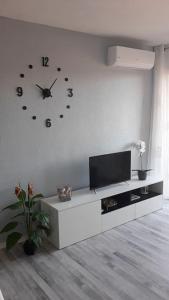 a living room with a tv and a clock on the wall at Apartamento acogedor in El Vendrell