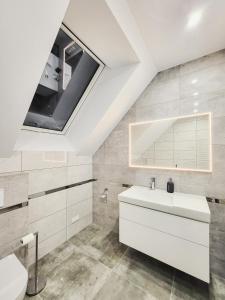 a bathroom with a white sink and a skylight at Domki na wzgórzu in Jarnołtówek