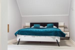 a bedroom with a bed with blue blankets and pillows at Domki na wzgórzu in Jarnołtówek