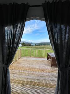 un porche con cortinas negras y un banco en una cubierta en STORR (caravan skye holidays), en Portree