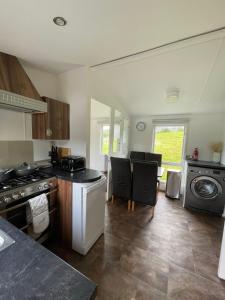 a kitchen with a stove and some chairs in it at STORR (caravan skye holidays) in Portree