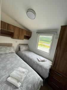 um pequeno quarto com 2 camas e uma janela em STORR (caravan skye holidays) em Portree