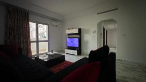 a living room with a couch and a flat screen tv at Appartement Slim centre sousse in Sousse