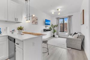 a kitchen and living room with white cabinets and a table at Luxe 1 BR apt EWR Prudential Center in Elizabeth
