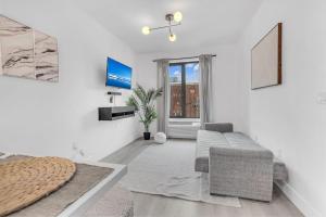 a white living room with a couch and a window at Luxe 1 BR apt EWR Prudential Center in Elizabeth