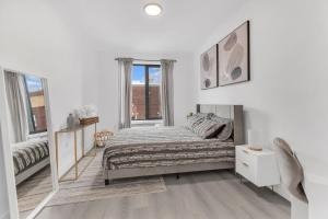 a white bedroom with a bed and a window at Luxe 1 BR apt EWR Prudential Center in Elizabeth