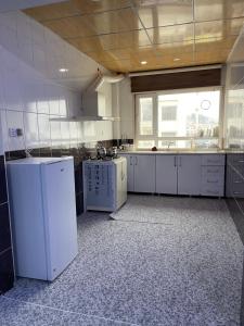 duża kuchnia z białymi urządzeniami i dużym oknem w obiekcie Zirka Apartments Duhok w mieście Dahuk