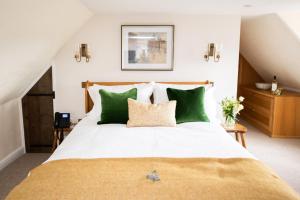 a bedroom with a large bed with green pillows at The Lion in East Bergholt