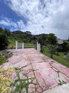 une passerelle en pierre dans une cour avec une clôture blanche dans l'établissement Rupe Rupe Lodge, à Uturoa