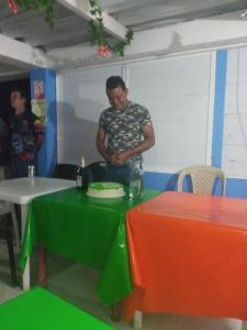 mężczyzna stojący obok stołu z tortem w obiekcie Posada Valerie w mieście Providencia