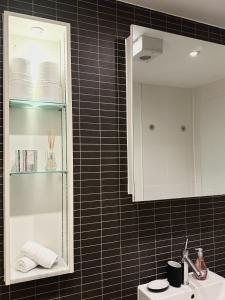 a black tiled bathroom with a sink and a mirror at Kings Cross City Apartment in London